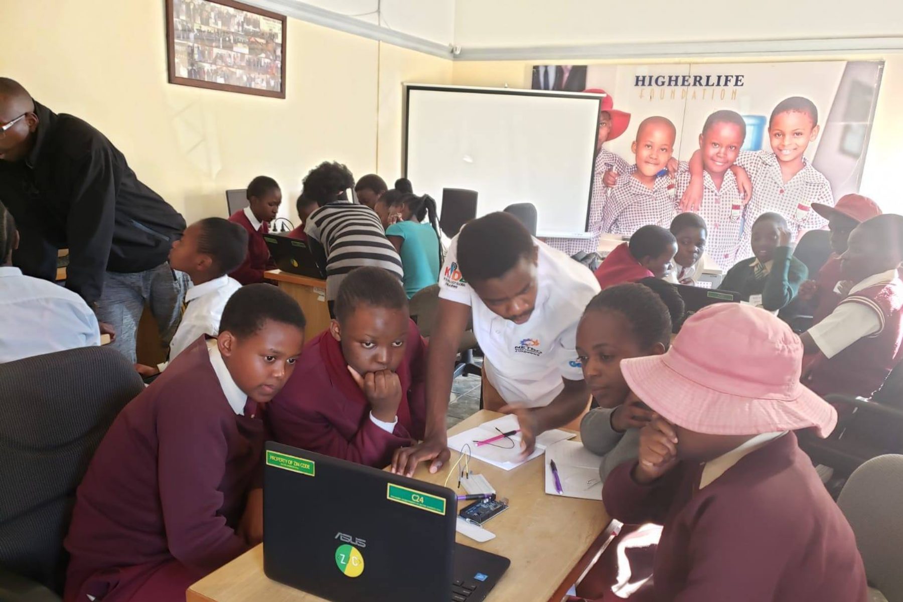 Students in school uniform crowded around laptops