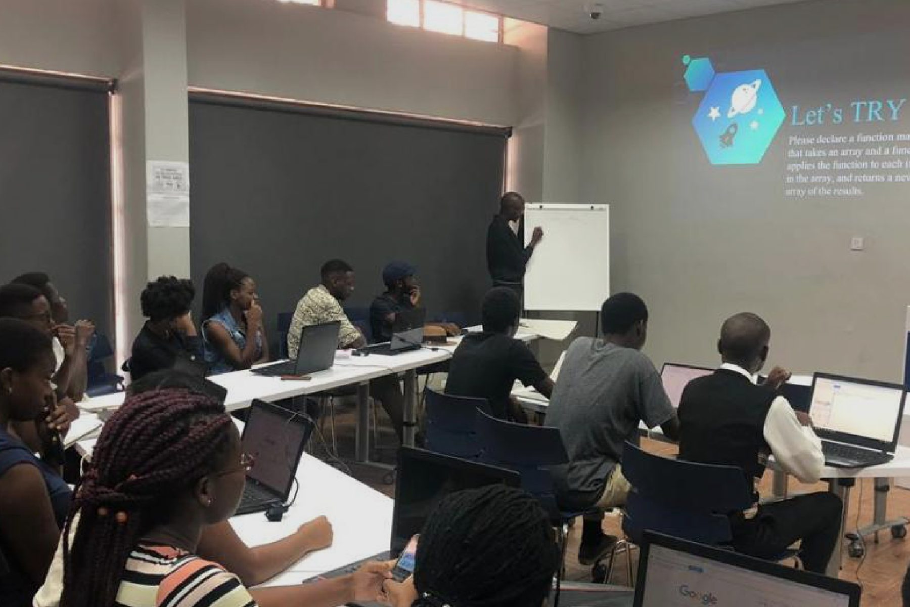 A room of students at laptops facing a projected slide